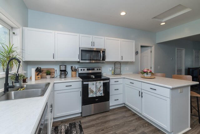 700 6th St E, Saint Paul, MN 55106 - kitchen with stainless steel appliances, a peninsula, white cabinets, light countertops, and recessed lighting
