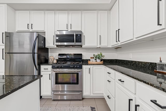 2566 Ellis Ave Unit 103, Saint Paul, MN 55114 - kitchen featuring appliances with stainless steel finishes, light tile patterned floors, white cabinets, and dark stone countertops