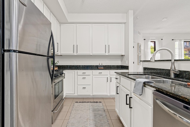 2566 Ellis Ave Unit 103, Saint Paul, MN 55114 - kitchen with stainless steel appliances, light tile patterned floors, white cabinetry, and dark stone counters