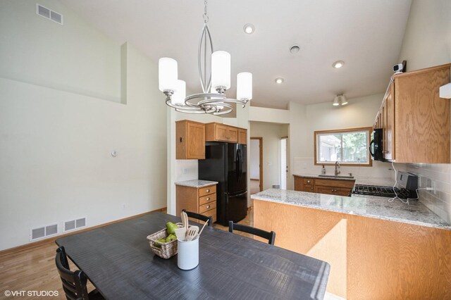 4224 93rd Ave N, Brooklyn Park, MN 55443 - kitchen featuring black appliances, a chandelier, a peninsula, brown cabinets, and light wood-type flooring