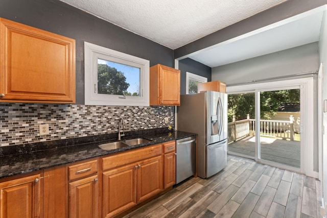 3204 5th Ave S, Minneapolis, MN 55408 - kitchen featuring stainless steel appliances, decorative backsplash, wood finished floors, a textured ceiling, and dark stone counters