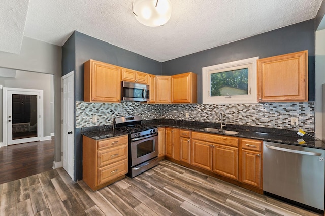 3204 5th Ave S, Minneapolis, MN 55408 - kitchen featuring stainless steel appliances, dark wood-style flooring, decorative backsplash, dark stone counters, and a textured ceiling