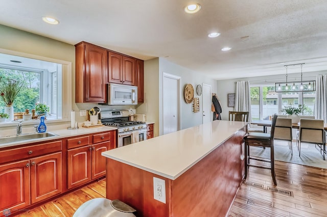 1800 Centre Sq, Moorhead, MN 56560 - kitchen featuring stainless steel gas range, white microwave, light wood-style flooring, light countertops, and recessed lighting