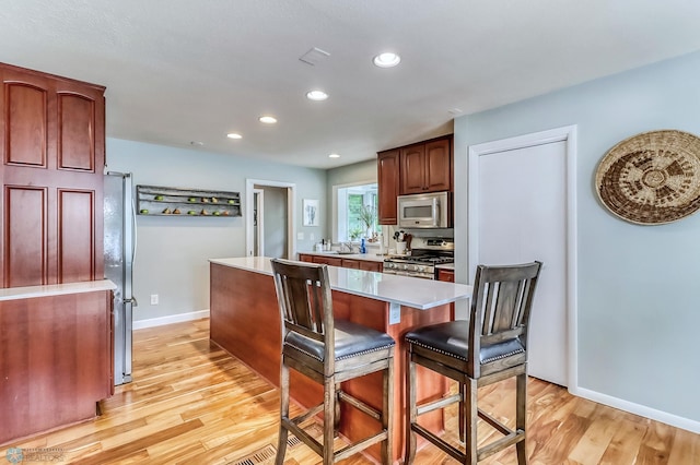 1800 Centre Sq, Moorhead, MN 56560 - kitchen featuring stainless steel appliances, light countertops, light wood-style flooring, a kitchen bar, and recessed lighting