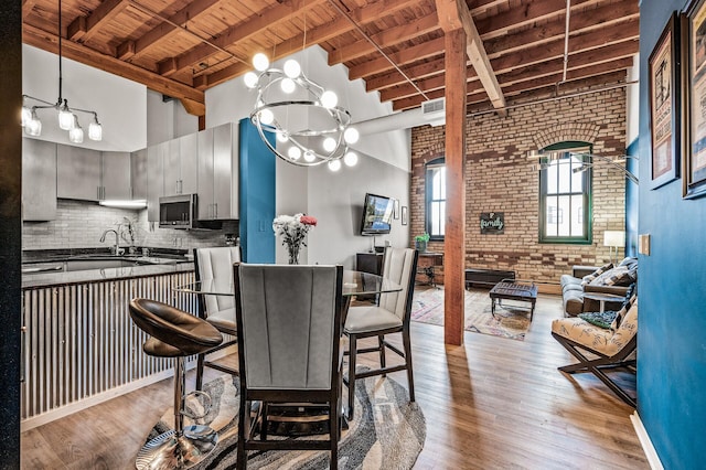 400 1st St Unit 611, Minneapolis, MN 55401 - kitchen with a wooden ceiling with exposed beams, brick wall, dark countertops, a high ceiling, and a chandelier