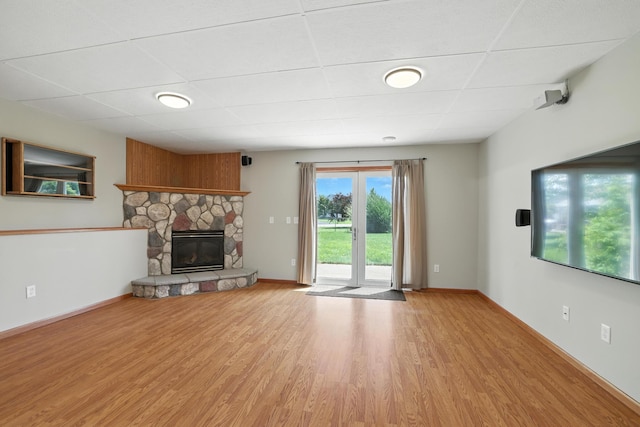 24155 Whispering Cir, East Bethel, MN 55005 - unfurnished living room with a paneled ceiling, light wood-type flooring, and a stone fireplace