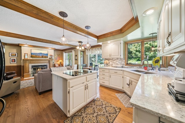 901 Grandview Dr, Hudson, WI 54016 - kitchen with a lit fireplace, a textured ceiling, white cabinetry, a kitchen island, and black electric cooktop