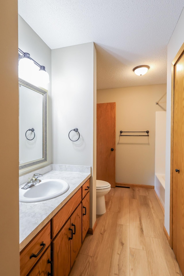 13752 Round Lake Blvd NW, Andover, MN 55304 - full bathroom featuring vanity, wood finished floors, a textured ceiling, and washtub / shower combination