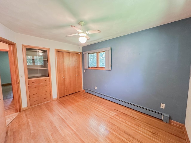 540 8th St, Bird Island, MN 55310 - unfurnished bedroom with a baseboard heating unit, light wood-style floors, a ceiling fan, and a closet