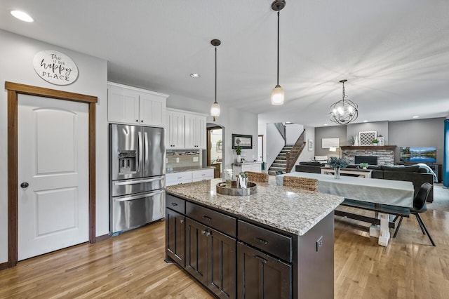1799 158th Ln NW, Andover, MN 55304 - kitchen with stainless steel fridge with ice dispenser, light wood-style flooring, white cabinets, a stone fireplace, and decorative backsplash