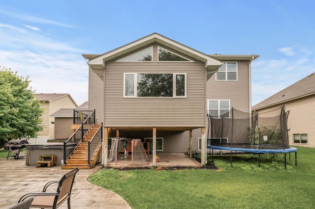 1799 158th Ln NW, Andover, MN 55304 - rear view of property featuring a patio, a hot tub, a trampoline, a lawn, and stairway