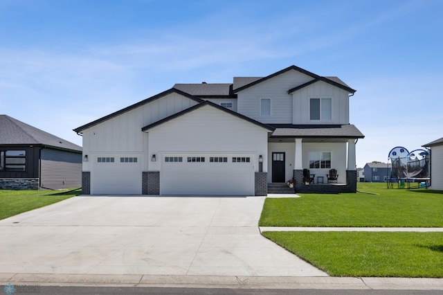 10128 Concord Dr, Horace, ND 58047 - view of front facade with board and batten siding, a front lawn, a garage, driveway, and brick siding