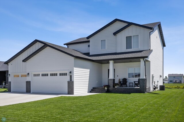 10128 Concord Dr, Horace, ND 58047 - view of front of house with covered porch, board and batten siding, an attached garage, a front yard, and driveway
