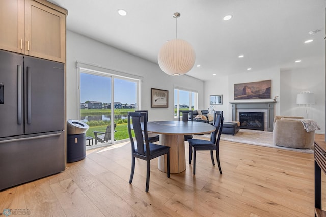 10128 Concord Dr, Horace, ND 58047 - dining space featuring a glass covered fireplace, light wood finished floors, recessed lighting, and a water view