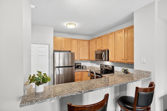545 1st St Unit 400, Minneapolis, MN 55401 - kitchen with appliances with stainless steel finishes, light stone counters, a breakfast bar area, and a peninsula
