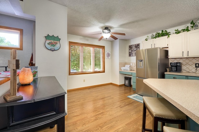 19161 Zane St NW, Elk River, MN 55330 - kitchen with stainless steel fridge, decorative backsplash, a ceiling fan, white cabinets, and light wood-style flooring