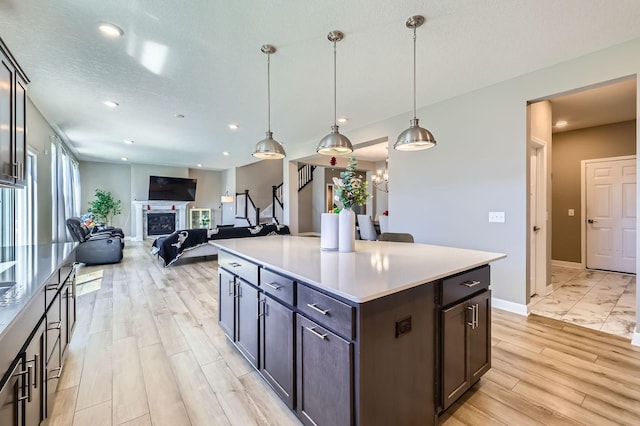 11887 73rd St NE, Otsego, MN 55301 - kitchen with dark brown cabinetry, light wood finished floors, a center island, recessed lighting, and light countertops