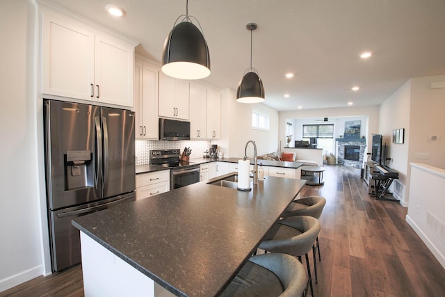 1267 Naser Way, New Richmond, WI 54017 - kitchen featuring stainless steel appliances, white cabinets, a center island with sink, dark wood-type flooring, and tasteful backsplash