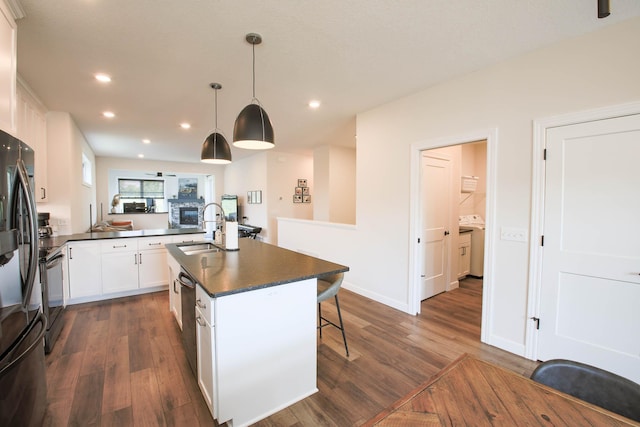 1267 Naser Way, New Richmond, WI 54017 - kitchen featuring dark countertops, dark wood-type flooring, recessed lighting, appliances with stainless steel finishes, and a kitchen bar