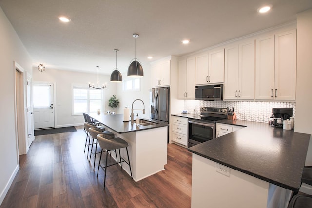 1267 Naser Way, New Richmond, WI 54017 - kitchen featuring appliances with stainless steel finishes, dark countertops, a breakfast bar, a chandelier, and tasteful backsplash