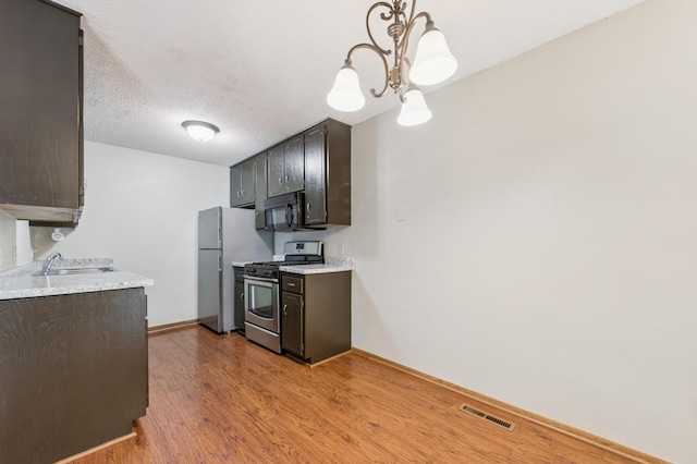 510 78th Ave NE, Spring Lake Park, MN 55432 - kitchen with stainless steel range with gas cooktop, black microwave, light countertops, wood finished floors, and dark brown cabinetry