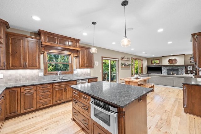 1899 White Oak Dr, Chaska, MN 55318 - kitchen featuring a kitchen island, decorative backsplash, light wood-style floors, dishwasher, and a fireplace