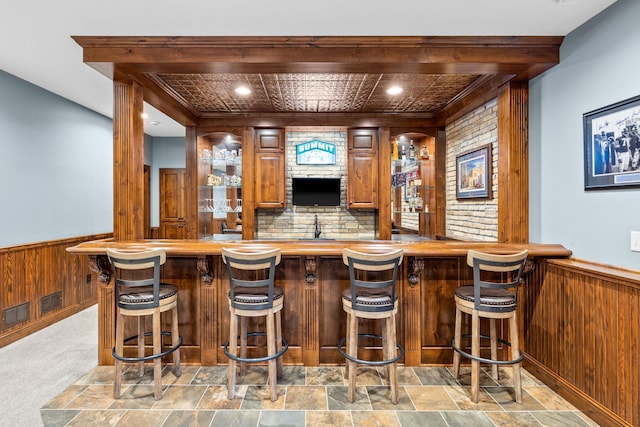 1899 White Oak Dr, Chaska, MN 55318 - indoor wet bar featuring wood walls, wainscoting, and stone finish floors