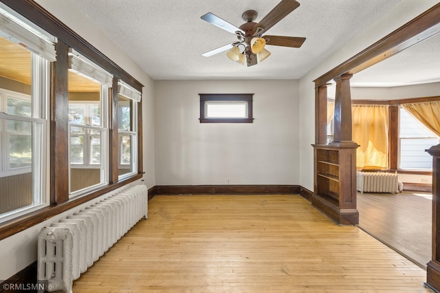 727 Virginia St, Saint Paul, MN 55103 - unfurnished room with radiator, a textured ceiling, ceiling fan, and light wood-style flooring