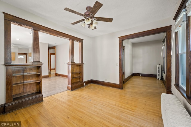727 Virginia St, Saint Paul, MN 55103 - unfurnished room with radiator heating unit, light wood-type flooring, ceiling fan, and ornate columns