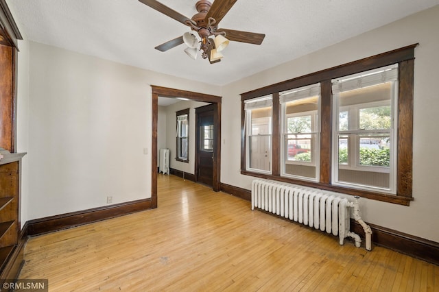 727 Virginia St, Saint Paul, MN 55103 - unfurnished room with radiator heating unit, light wood-style floors, and a ceiling fan