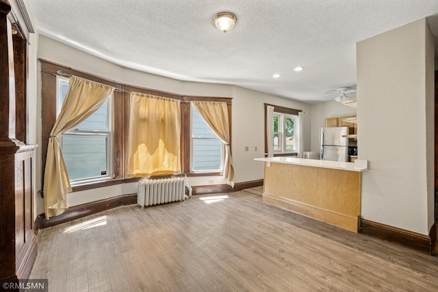 727 Virginia St, Saint Paul, MN 55103 - unfurnished living room featuring radiator, wood finished floors, ceiling fan, a textured ceiling, and recessed lighting