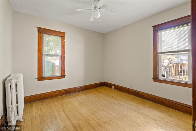 727 Virginia St, Saint Paul, MN 55103 - spare room with radiator heating unit, light wood-style floors, and a ceiling fan