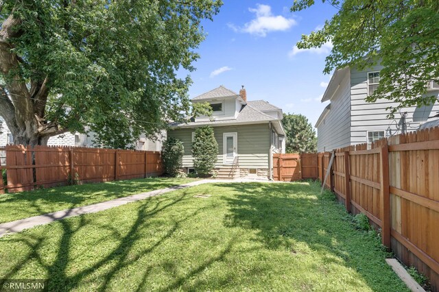 727 Virginia St, Saint Paul, MN 55103 - rear view of property with entry steps, a chimney, a fenced backyard, and a shingled roof