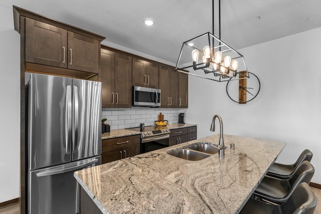 12910 Brenly Way, Rogers, MN 55374 - kitchen featuring appliances with stainless steel finishes, dark brown cabinets, a kitchen island with sink, decorative backsplash, and recessed lighting