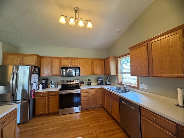 1070 20th St NE, Owatonna, MN 55060 - kitchen with stainless steel appliances, lofted ceiling, brown cabinetry, light wood finished floors, and light countertops