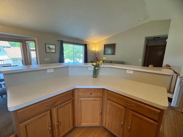 1070 20th St NE, Owatonna, MN 55060 - kitchen with light countertops, light wood-style floors, lofted ceiling, open floor plan, and brown cabinetry