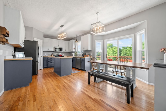 2418 Thrush St, Shakopee, MN 55379 - kitchen featuring appliances with stainless steel finishes, a center island, light countertops, light wood-type flooring, and white cabinetry