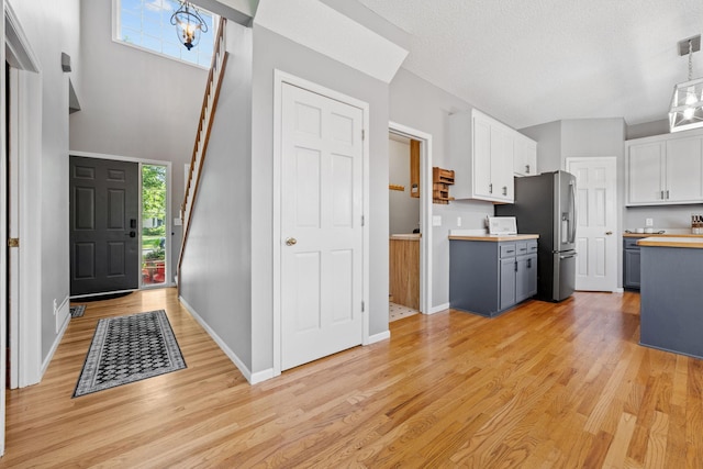 2418 Thrush St, Shakopee, MN 55379 - kitchen with stainless steel fridge, white cabinetry, light wood-type flooring, and pendant lighting