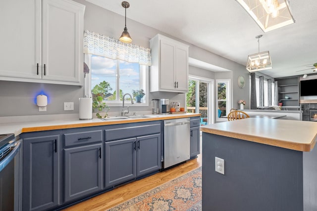 2418 Thrush St, Shakopee, MN 55379 - kitchen featuring stainless steel dishwasher, range, light wood-style flooring, light countertops, and decorative light fixtures