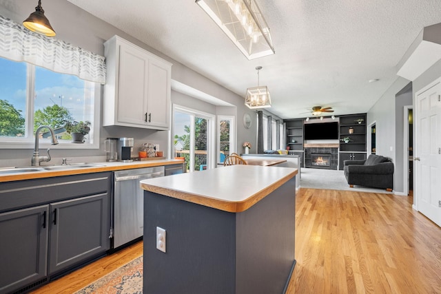 2418 Thrush St, Shakopee, MN 55379 - kitchen featuring dishwasher, gray cabinetry, pendant lighting, a warm lit fireplace, and a kitchen island