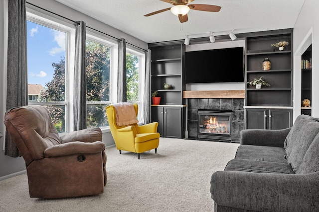 2418 Thrush St, Shakopee, MN 55379 - carpeted living area with ceiling fan, a tiled fireplace, a textured ceiling, and track lighting