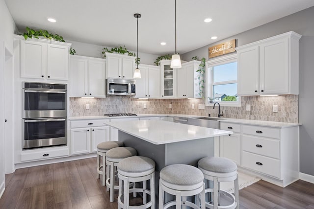 12745 39th St NE, Saint Michael, MN 55376 - kitchen featuring stainless steel appliances, a kitchen bar, a center island, white cabinets, and dark wood-type flooring