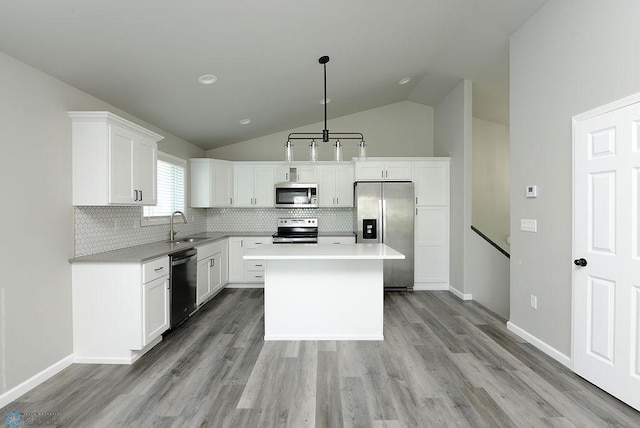 1040 Barnes Dr, West Fargo, ND 58078 - kitchen featuring stainless steel appliances, light wood-style floors, vaulted ceiling, backsplash, and white cabinets