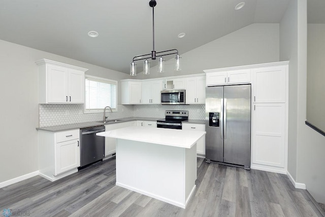 1040 Barnes Dr, West Fargo, ND 58078 - kitchen with appliances with stainless steel finishes, backsplash, white cabinetry, wood finished floors, and vaulted ceiling