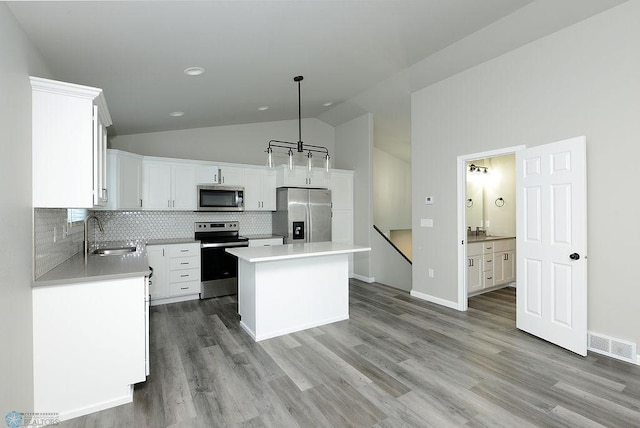 1040 Barnes Dr, West Fargo, ND 58078 - kitchen with stainless steel appliances, decorative backsplash, white cabinets, light wood-style flooring, and high vaulted ceiling