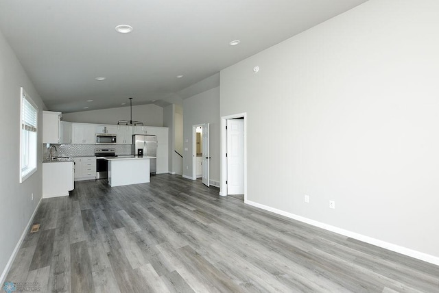 1040 Barnes Dr, West Fargo, ND 58078 - unfurnished living room featuring lofted ceiling, wood finished floors, and recessed lighting