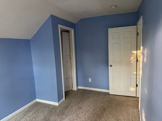 663 Smith Ave S, Saint Paul, MN 55107 - unfurnished bedroom featuring carpet flooring and vaulted ceiling