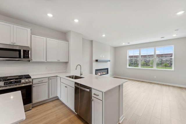 7407 E Ramsey Pkwy NW, Ramsey, MN 55303 - kitchen featuring appliances with stainless steel finishes, a peninsula, open floor plan, light wood finished floors, and tasteful backsplash