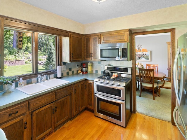 461 Dudley Ave, Shoreview, MN 55126 - kitchen featuring stainless steel appliances, backsplash, light countertops, light wood-style flooring, and brown cabinets