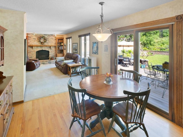 461 Dudley Ave, Shoreview, MN 55126 - dining room featuring a brick fireplace, light wood-style flooring, and a textured ceiling